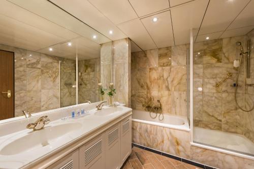 ein Bad mit einer Badewanne, einem Waschbecken und einer Dusche in der Unterkunft Maritim Hotel Stuttgart in Stuttgart