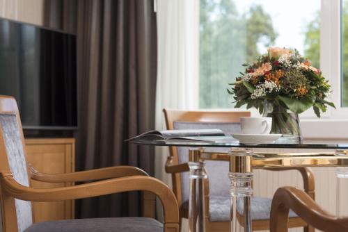 a room with a table with a vase of flowers on it at Maritim Hotel Stuttgart in Stuttgart