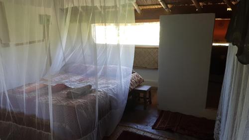 a bedroom with a bed with curtains and a window at Mufasa Eco Lodge in Monkey Bay