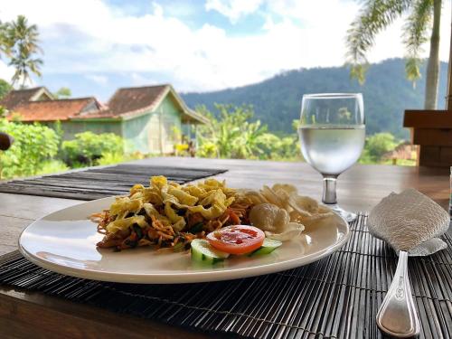 een bord eten op tafel met een glas wijn bij Kubu Taru in Sidemen