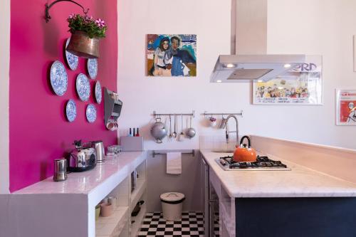 una cucina con parete rosa e piano cottura di Rome As You Feel - Vittorio Colorful Design Apartment a Roma
