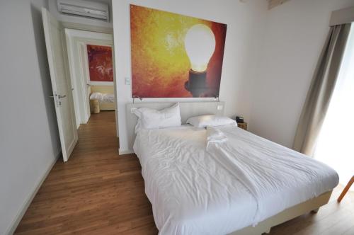a bedroom with a white bed and a painting on the wall at Energy Hotel in Calceranica al Lago