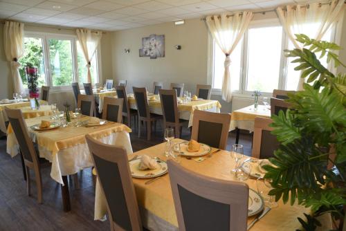 a dining room with tables and chairs and windows at Hôtel les Bergeronnettes in Champagneux