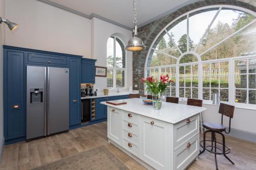 een keuken met blauwe en witte kasten en een groot raam bij The Lake House, Wansfell Holme, Windermere in Ambleside