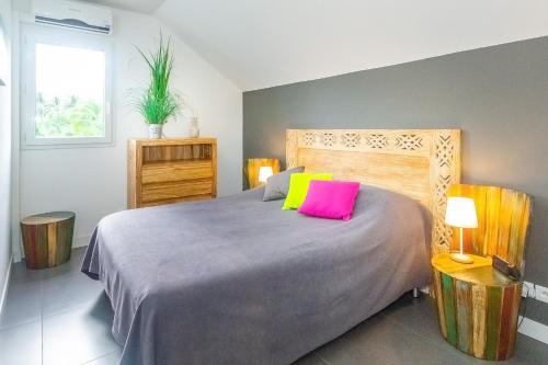 una camera da letto con un letto con cuscini rosa e gialli di Lagoon ! Jolie villa à 2 pas du lagon de la Saline a La Saline Le Bains