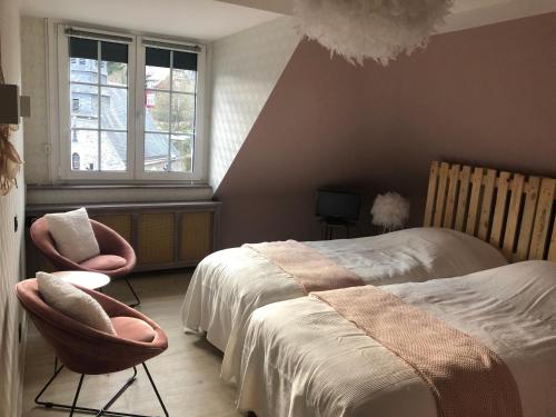 a bedroom with a bed and two chairs and a window at Hostellerie de la Chapelle in Malmedy