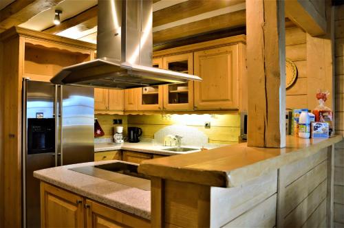 une cuisine avec des armoires en bois et un réfrigérateur en acier inoxydable dans l'établissement Residence le Dahu, à Saint-Jean-de-Sixt