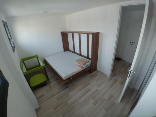 una piccola camera con letto e sedia verde di Luxusný apartmán s bezplatným parkovaním v objekte a self-checking a Brenner