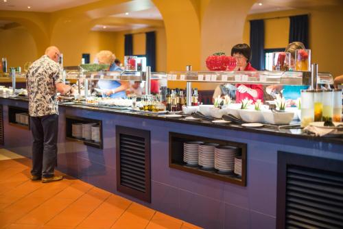 Un hombre preparando comida en un buffet en un restaurante. en Vila Gale Tavira, en Tavira