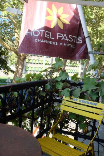 a yellow bench next to a sign on a fence at Logis Pastis in Maastricht