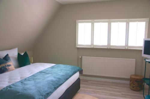 a bedroom with a bed and two windows and a television at Meinsbur Boutique Hotel in Bendestorf
