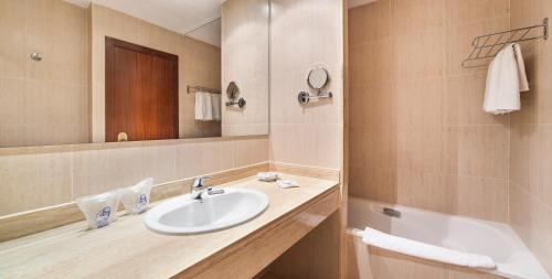 a bathroom with a sink and a mirror and a tub at Garbi Cala Millor in Cala Millor