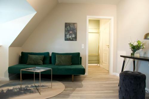 a living room with a green couch and a table at Meinsbur Boutique Hotel in Bendestorf