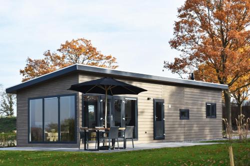 a small shed with a table and chairs and an umbrella at Strandparc Nulde in Putten