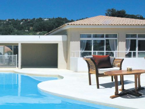 un patio avec une table et des chaises à côté d'une piscine dans l'établissement Lagrange Vacances Les Bastides des Chaumettes, à Montauroux