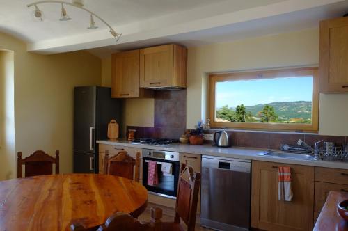 cocina con mesa de madera y ventana grande en Chez la Nonna, en Saint-Jean-le-Centenier