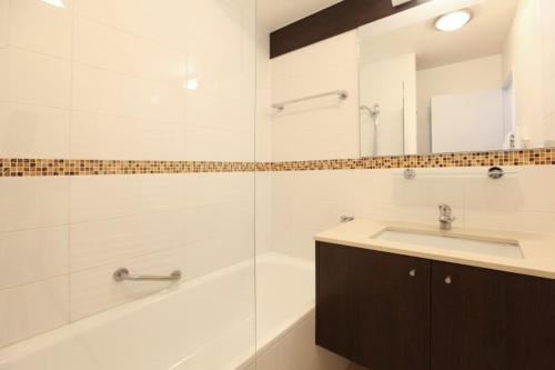 een badkamer met een wastafel, een bad en een spiegel bij VVF Résidence Arcachon in Arcachon