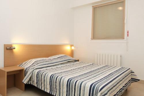 1 dormitorio con 1 cama con cabecero de madera y ventana en VVF Résidence Arcachon en Arcachón