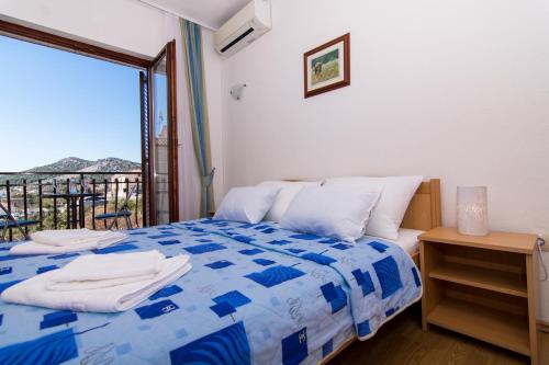 a bedroom with a blue and white bed and a balcony at Apartments Jozic in Seget Vranjica
