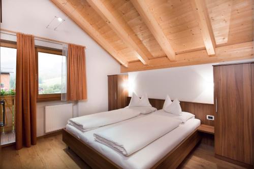a bedroom with a large bed with a wooden ceiling at B&B Residence Adria in Corvara in Badia