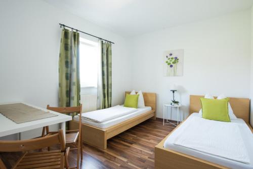 Habitación pequeña con 2 camas y mesa. en Pension Rosenhof, en Linz