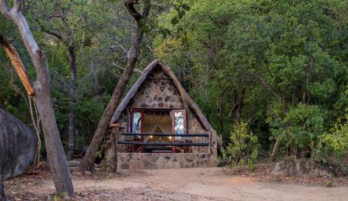 a small stone house in the middle of a forest at Big Cave Camp in Matopos