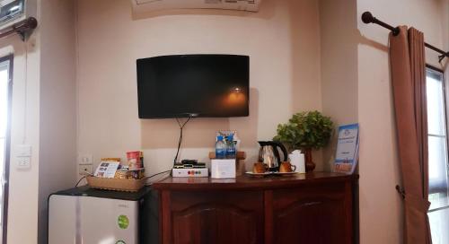 a room with a tv on a wall with a refrigerator at Bua Patumma Resort in Mae Sai