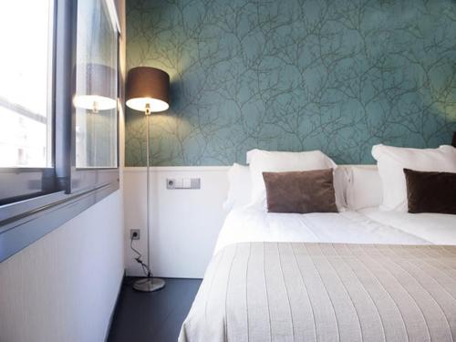 a bedroom with a white bed and a green wall at Barcelona Fifteen central Aparthotel in Barcelona