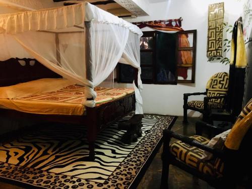 a bedroom with a bed with a mosquito net at Boutique Hotel Nyumbani Tembo in Watamu