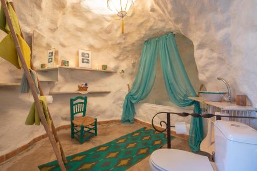 a bathroom in a cave with a toilet and a chair at Casa Cueva Muntasal in Monachil