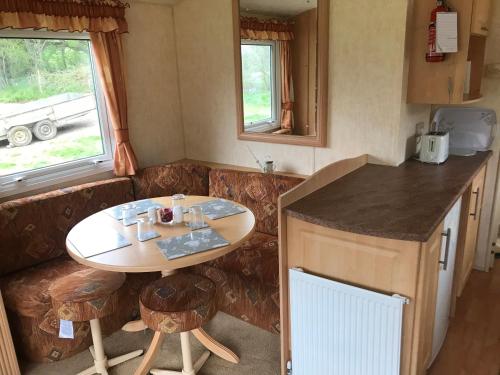a small kitchen with a table and chairs in a caravan at Yeovil Accomodation Business & Pleasure, 2 dble Bedrooms, Bathroom en-suite, Kitchen, Lounge, Diner, Garden, 365 acres Forest & Streams, Workers huts available with lrge Van parking in Montacute