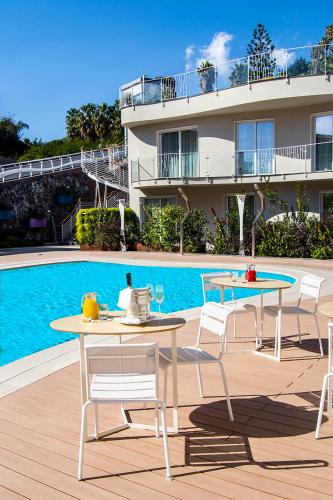 a patio with two tables and chairs next to a pool at Ciclope Resort in Acitrezza