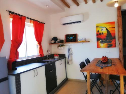 a kitchen with a wooden table and a kitchen with red curtains at Maisha Marefu Apartments in Kiwengwa