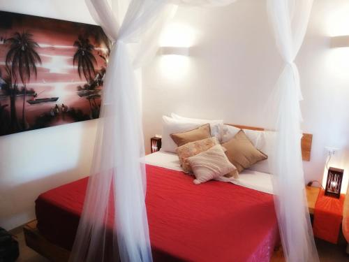 a bedroom with a bed with red sheets and pillows at Maisha Marefu Apartments in Kiwengwa