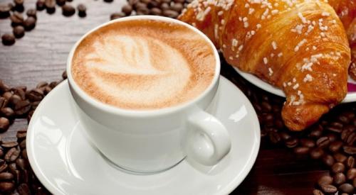 a cup of coffee and a croissant and coffee beans at Suite 01 in Montesarchio