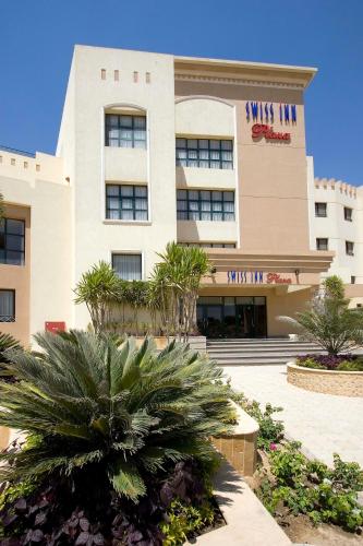 a building with a palm tree in front of it at Swiss Inn Plaza Hotel in 6th Of October
