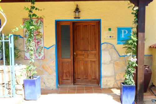 una puerta de madera de una casa con dos macetas en Hospedería Ancladero, en Mojácar