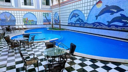 una piscina con mesas y sillas y un mural de delfines en Exoticky apartman en Hurghada