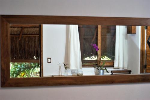 a mirror reflection of a window with flowers on a table at Hotel Boutique TerraNova in Tulum