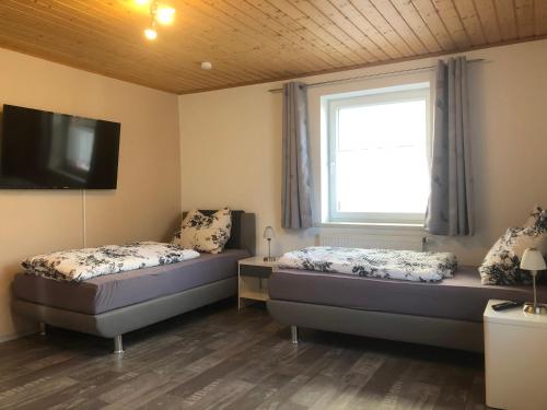 zwei Betten in einem Zimmer mit Fenster und Fernseher in der Unterkunft SAD100 - Gemütliche Monteurwohnungen in Schwandorf in Schwandorf in Bayern