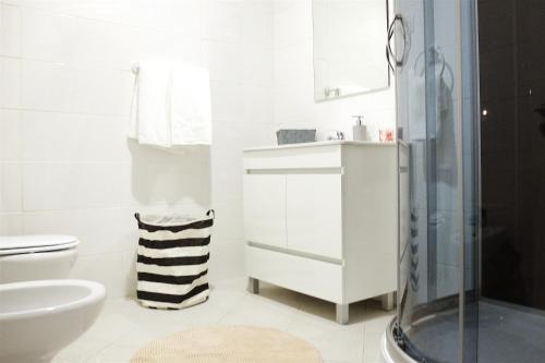a white bathroom with a sink and a toilet at Family House in Aveiro