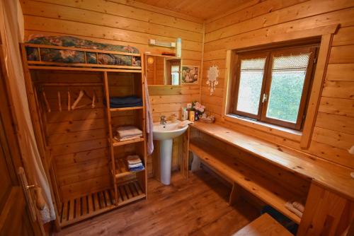 - une salle de bains en rondins avec lavabo et fenêtre dans l'établissement Chalet à fleur de rêve, à Maroilles