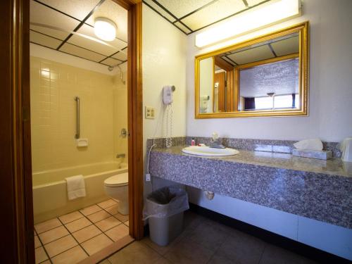 a bathroom with a sink and a toilet and a mirror at Days Inn by Wyndham Clinton in Clinton