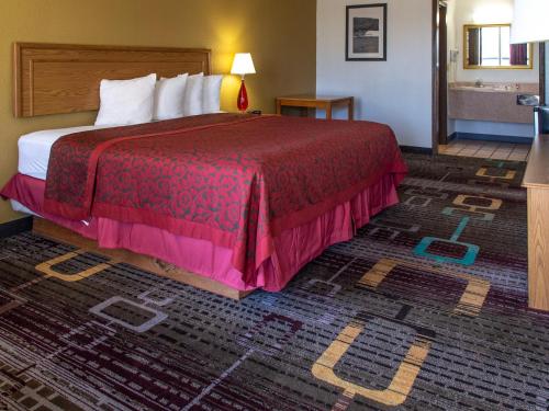 a hotel room with a bed with a red bedspread at Days Inn by Wyndham Clinton in Clinton