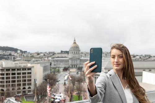 a woman taking a picture of a city with her cell phone at Yotel San Francisco in San Francisco