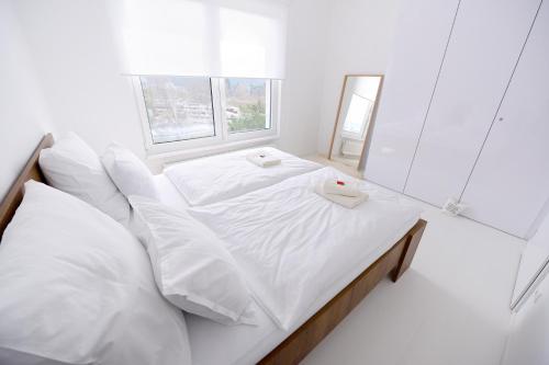 Dormitorio blanco con cama con sábanas y almohadas blancas en Center Aupark Apartment en Piešťany