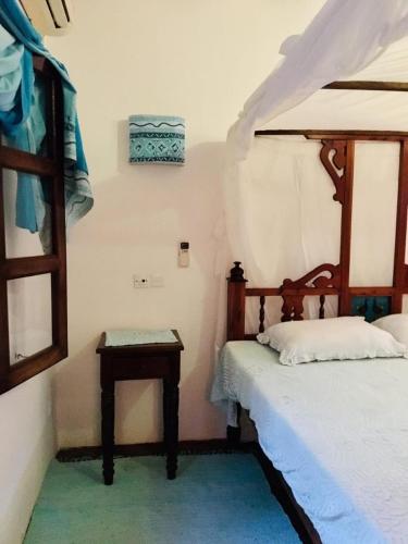 a bedroom with a bed and a table next to a bed at Boutique Hotel Nyumbani Tembo in Watamu