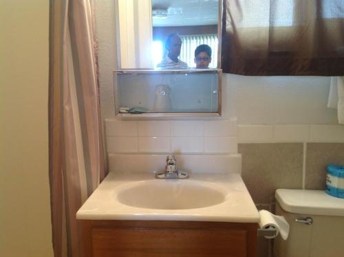 a bathroom with a sink and a person in the mirror at Budget Inn Motel Chemult in Chemult