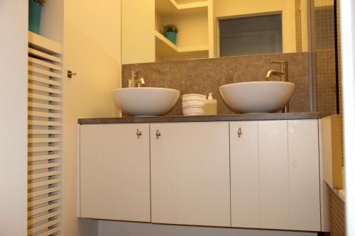 a bathroom with two sinks on top of cabinets at Residentie TYL - Leopoldlaan 122 in Knokke-Heist