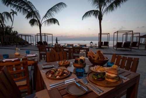 a table with food on a beach with palm trees at The Residence Maldives at Dhigurah in Gaafu Alifu Atoll